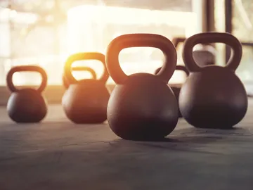 A row of kettlebells are lined up on the floor.
