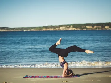 A woman is doing a handstand on the beach