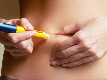 A person is using a yellow pen to cut off the skin of their stomach.