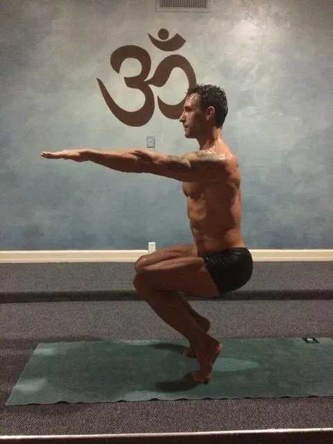 A man is doing yoga in front of an om sign.
